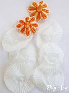 three orange and white paper flowers sitting on top of each other next to one another