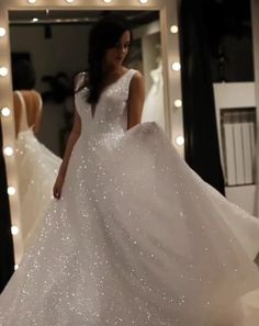 a woman in a white wedding dress is walking through a room with lights on the walls