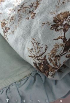 a close up of a pillow on top of a bed with ruffles and flowers