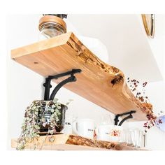 a wooden shelf with glass jars and plants on it, hanging from the ceiling over a kitchen counter