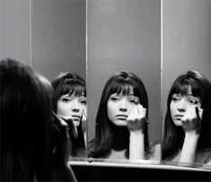 three women looking at their faces in the mirror