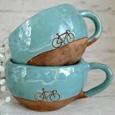 two tea cups with bicycles painted on them are sitting next to each other in front of white flowers