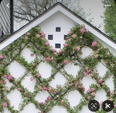 a white house with pink flowers growing on it