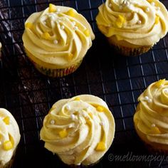 cupcakes with yellow frosting sitting on a cooling rack