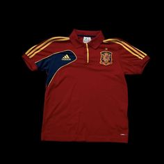 a red shirt with yellow and blue stripes on the chest, in front of a black background