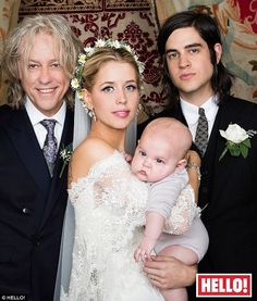 two men and a woman are posing for a photo with a baby in their arms