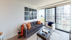 a living room filled with furniture next to a large window covered in lots of windows