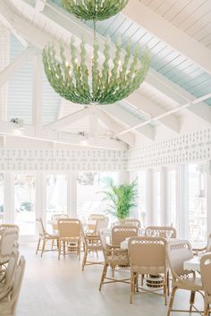 a dining room filled with lots of tables and chairs under a chandelier hanging from the ceiling