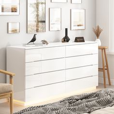 a white dresser with pictures on the wall