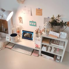 a desk with a computer, keyboard and various other items on it in front of a lamp