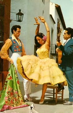 a man and two women dancing in front of a house