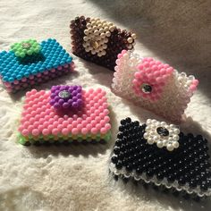 four small beaded purses sitting on top of a white blanket next to each other