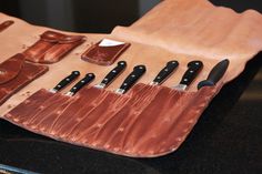 a leather case with knives and knife sheaths in it on a black counter top