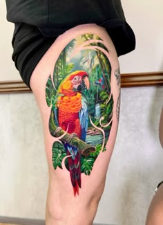 a colorful parrot sitting on top of a tree branch next to a woman's thigh