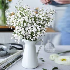 white flowers are in a vase on a table