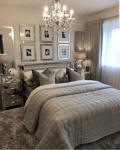 a bedroom with a large bed, chandelier and pictures on the wall above it