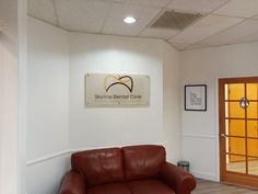 a brown leather couch sitting in front of a white wall next to a wooden door