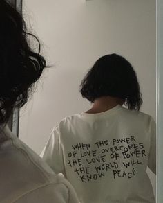 a woman is looking at herself in the mirror wearing a t - shirt that says when the power of love overcomes the love of power, the world will know peace