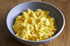 a bowl filled with scrambled eggs on top of a wooden table