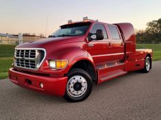 a red truck is parked on the side of the road in front of some grass