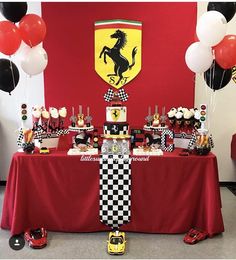 a red table topped with lots of desserts next to black and white balloons in the shape of ferrari