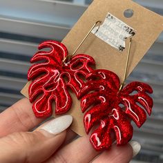 a pair of red earrings with monster leaves on them