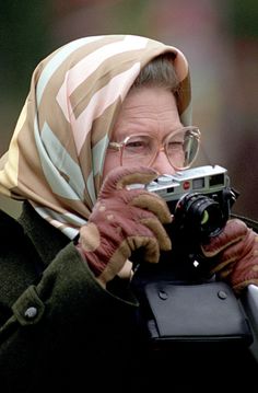 an old man holding a camera up to his face while wearing a headscarf