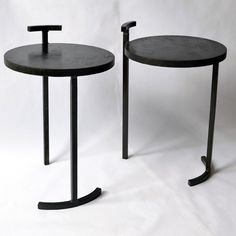 two black tables sitting next to each other on a white background, one is round and the other has curved legs