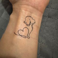 a small tattoo on the wrist of a person with a dog's head and heart