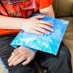 a young boy sitting on a couch holding a blue piece of paper