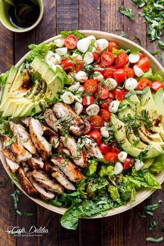 a salad with chicken, lettuce, tomatoes and avocado on it