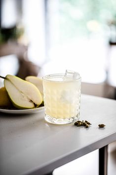 a glass filled with water sitting on top of a table next to two pears