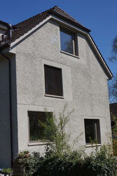 a white house with three windows and bushes