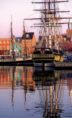 an old sailing ship is docked in the water near some buildings and other colorful houses