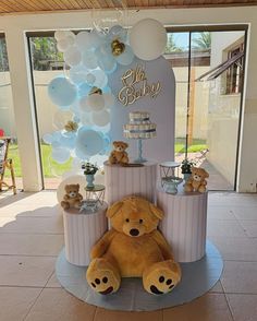 a teddy bear sitting in front of a cake with balloons on the top and around it