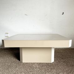 a white coffee table sitting on top of a carpeted floor next to a wall