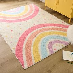 a child's rug with a rainbow design on the floor next to a crayon book