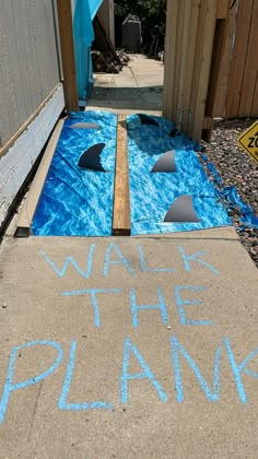 the sidewalk has been painted with blue chalk and it says walk the plank on it