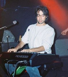 a man sitting at a keyboard in front of a microphone