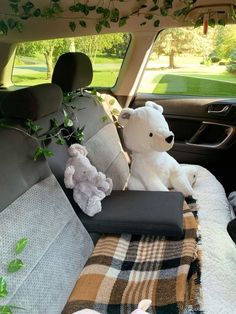 a teddy bear sitting in the back seat of a car with blankets and pillows on it