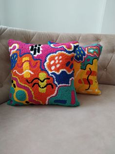 two colorful pillows sitting on top of a couch