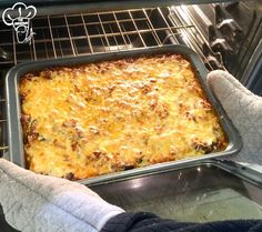 a person in gloves is taking a casserole out of the oven