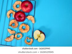 an apple, donut holes and two apples on a cooling rack against a blue background