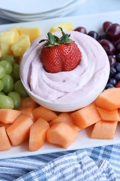 a white plate topped with fruit and veggies next to a bowl of dip