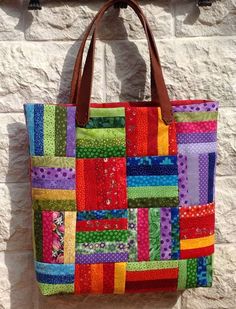 a multicolored patchwork bag hanging on a brick wall