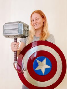 a woman in grey shirt holding a shield and hammer