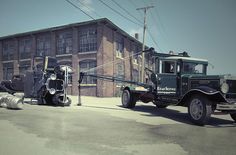 an old fashioned tow truck parked in front of a building