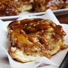 two desserts sitting on top of white plates covered in caramel sauce and pecans