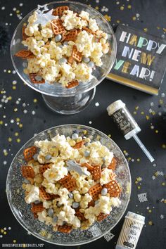 two glass bowls filled with popcorn and marshmallows on top of a table