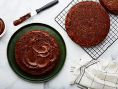 two chocolate cakes sitting on top of a green plate next to a knife and fork